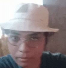 a man wearing a white hat and glasses is taking a selfie .