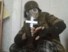 a man wearing a gas mask is holding a cross in his hand .