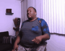 a man is dancing in a living room with a couch and blinds .