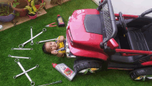 a baby is laying on the grass next to a toy car and a bottle of kds oil