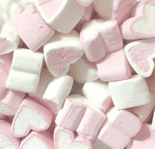 a pile of pink and white heart shaped marshmallows on a table