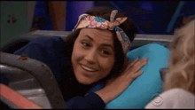 a woman wearing a headband is sitting on a blue pillow and smiling .