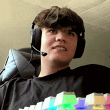 a young man wearing headphones and a microphone is sitting in a chair holding a keyboard .