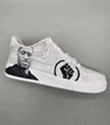 a pair of white sneakers with a picture of a man and a fist on them .