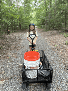 a girl pushes a cart with buckets on it