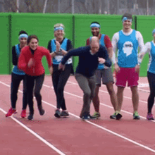 a group of people are running on a track and one of them is wearing a blue shirt with a ghost on it