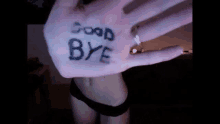 a woman in black underwear is holding up her hand with the words good bye written on it .