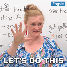 a woman says let 's do this while standing in front of a whiteboard