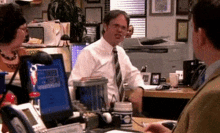 a man sits at a desk in front of a computer with a cup of coffee in front of him