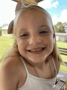 a young girl with a bow in her hair smiles for the camera