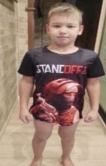 a young boy is standing in a hallway wearing a t-shirt with a picture of a man on it .