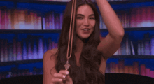 a woman with long hair is holding a tuning fork in her hand .