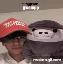 a man wearing a red make america great again hat holds a stuffed animal