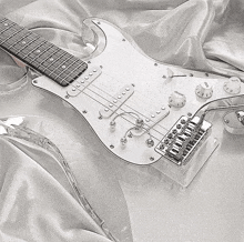 a white electric guitar is laying on a white cloth with the volume and tone knobs visible