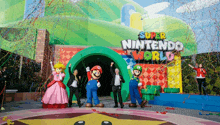 a group of mario characters are standing in front of a sign that says super nintendo world