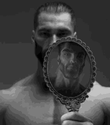 a man with a beard is looking at himself in a small mirror