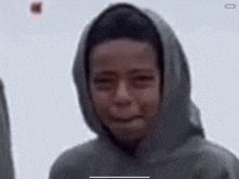 a boy wearing a hoodie is making a funny face .