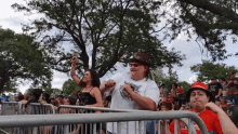 a group of people standing behind a fence with one man wearing a hat that says ' texas ' on it .