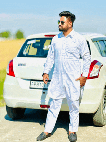 a man in a white kurta stands in front of a white car with a license plate that says pb10fp