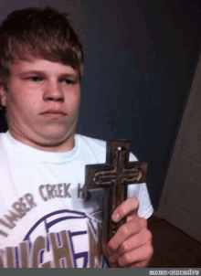 a young man holding a cross wearing a shirt that says lumber creek