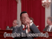 a man in a suit and tie is laughing in a courtroom in front of a group of people .