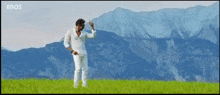 a man in a white shirt is dancing in a field with mountains in the background and eros written on the bottom