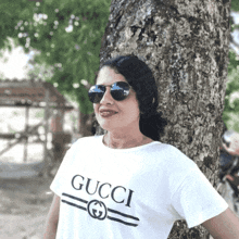 a woman wearing sunglasses and a white shirt that says gucci