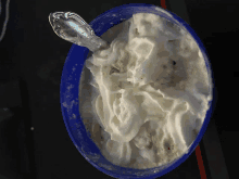 a blue bowl filled with whipped cream and a silver spoon