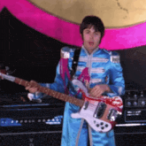 a man in a blue jacket playing a guitar
