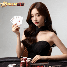 a woman in a black dress is holding a hand of playing cards in front of a sign that says agen69