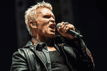 a man singing into a microphone wearing a leather jacket