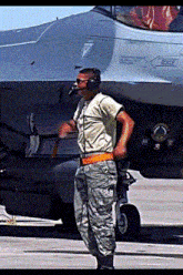 a man in a military uniform stands in front of a fighter jet with the word rescue on the side