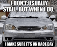 a silver ford car with snow on the windshield is parked in a driveway .