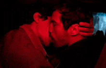 a man and a woman are kissing in a car under red lights .