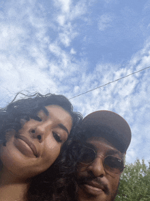 a man and a woman are posing for a picture and the man is wearing ray-ban sunglasses