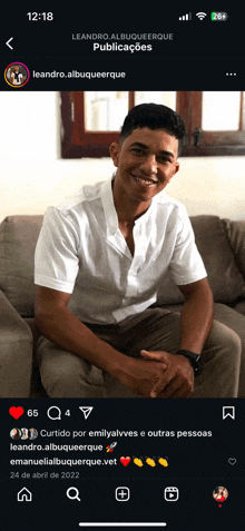 a man is sitting on a couch with his hands folded in front of him