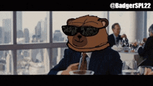 a cartoon of a teddy bear wearing sunglasses and a suit with the hashtag badgerspl22 at the bottom