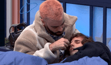 a man with pink hair is touching another man 's hair