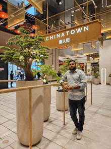 a man stands in front of a chinatown sign