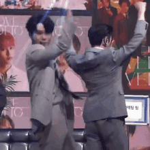 two men in suits are dancing on a stage in front of a poster that says love