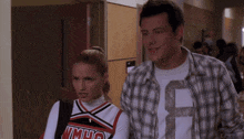 a cheerleader wearing a uniform that says vmhs stands next to a man in a plaid shirt