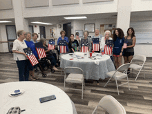 a group of people standing around a table with flags on it