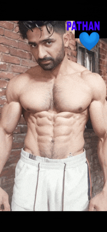 a man without a shirt is standing in front of a brick wall with the name pathan above him