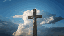 a cross with jesus on it against a cloudy blue sky