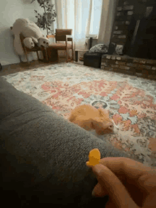 a cat is laying on a couch while a person holds a yellow object