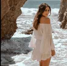 a woman in a white off the shoulder dress is standing in the water