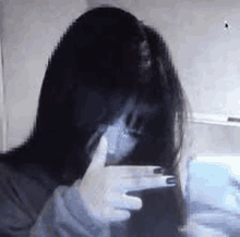 a woman is taking a selfie with her hands in front of her face .