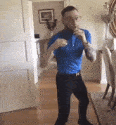 a man in a blue shirt and black pants is dancing in a living room
