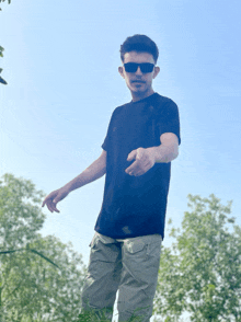 a young man wearing sunglasses and a black shirt is standing in a field