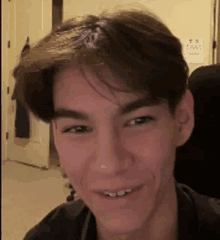 a close up of a young man 's face smiling in a room